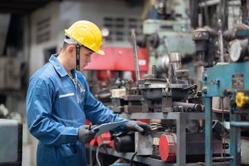 technician checking metal component at machine dump in factory