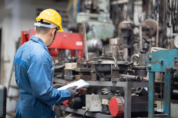 engineer checking metal component at machine receptacle in factory