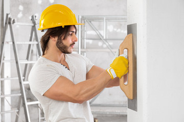 Plasterer finishing the surface of a white wall