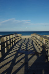 Lights and shadows on a wooden bridge leading to the sea