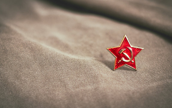 Red star with a sickle and a hammer on a background of fabric. Military attribute.