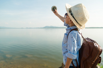 Side view of the boy holding a compass by the lake