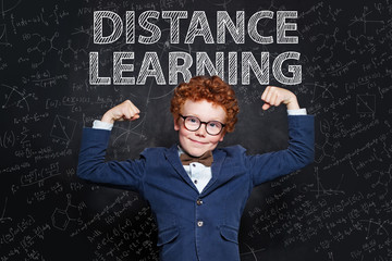 Strong child boy on blackboard background. Distance learning and happy kid concept