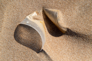 Fototapeta na wymiar Disposable plastic cup in the sand, causing pollution at Poço beach, near the city of João Pessoa, Paraíba, Brazil on September 29, 2012