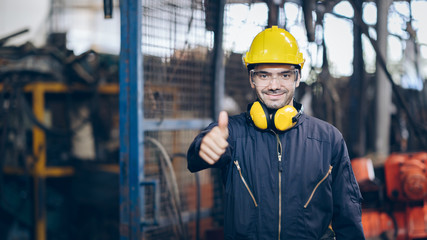Smile technician Engineer man thump up and hold portable radio in factory
