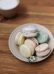 Colorful homemade macarons are lying on the brown wooden background.Cup of coffee. 