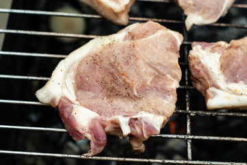A strip steak newly placed on a charcoal grill