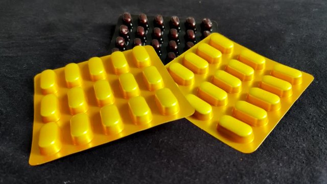 Slomo panning shot of yellow and brown tablet strips on a black table