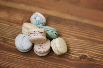 Colorful homemade macarons are lying on the brown wooden background. Pattern.