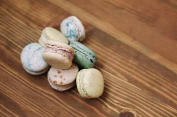 Colorful homemade macarons are lying on the brown wooden background. Pattern.