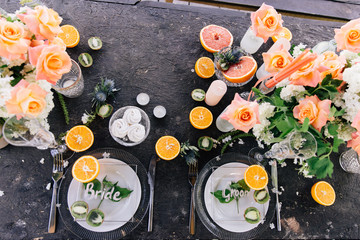 Plates for seating the bride and groom in a trend of glass on a dark wedding table with citrus fruit decorations