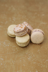 Yellow homemade macarons with blossom are lying on the golden background.
