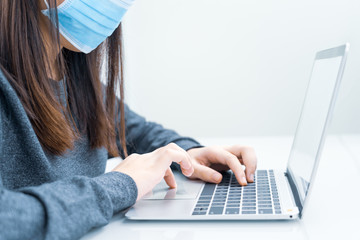 Woman using laptop on desk at home with wearing mask for protect Covid-19