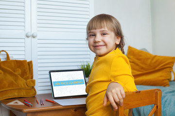 Cute child smiling and using laptop. Distance learning and on-line education concept