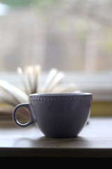 Cup of tea or coffee and open book at home. Selective focus.