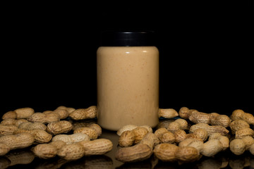 Ripe peanuts in husk and jar with peanutbutter