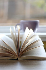 Cup of tea or coffee and open book at home. Selective focus.