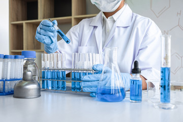 Female scientific researcher or doctor working in laboratory about virus and vaccine antiretroviral coronavirus covid19 researcher investigations with test tubes flask and blue liquid solution