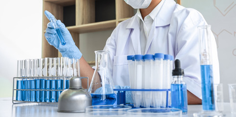 Female scientific researcher or doctor working in laboratory about virus and vaccine antiretroviral coronavirus covid19 researcher investigations with test tubes flask and blue liquid solution