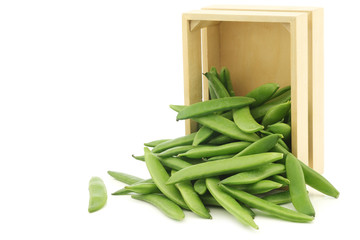 freshly harvested sugar snaps in a wooden box on a white background