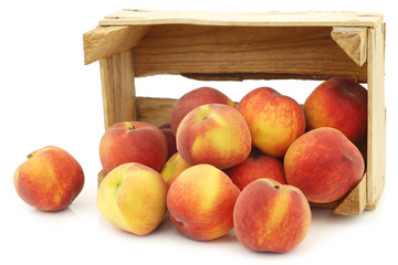 Fresh peaches in a wooden crate on a white background