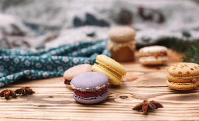 Homemade colorful macaroons are lying on the brown wooden table. Cup of coffee. Anise, honey and colorful tissue.