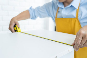 Men's hands hold a measuring tape measuring with flexible ruler for home renovation. repair,...