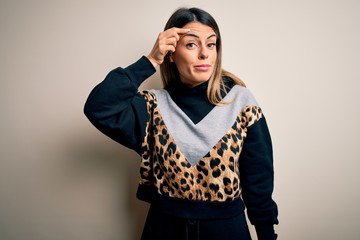 Young beautiful woman wearing casual sweatshirt standing over isolated white background pointing unhappy to pimple on forehead, ugly infection of blackhead. Acne and skin problem