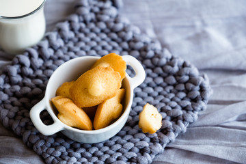 Madeleines miniatures fait maison dans un bol blanc et fond en laine gris