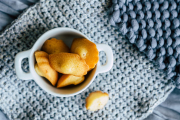 Madeleines miniatures fait maison dans un bol blanc et fond en laine gris