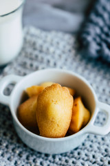 Madeleines miniatures fait maison dans un bol blanc et fond en laine gris