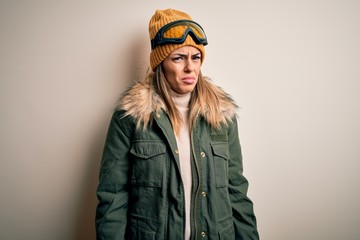 Young brunette skier woman wearing snow clothes and ski goggles over white background skeptic and nervous, frowning upset because of problem. Negative person.
