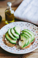 Tartines de pain de campagne avec des lamelles d'avocat assaisonnée à l'huile d'olive et poivre