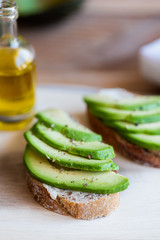 Tartines de pain de campagne avec des lamelles d'avocat assaisonnée à l'huile d'olive et poivre