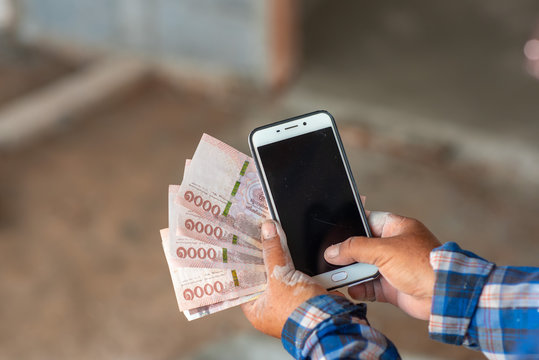 The hands of the construction workers holding banknotes and mobile phones - Powered by Adobe