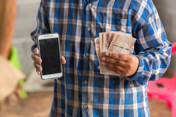 The hands of the construction workers holding banknotes and mobile phones