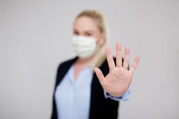 business and corona virus pandemic concept - business woman in medical mask showing stop sign