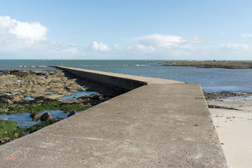 Une des plages de la ville de Loctudy en Bretagne dans le Finistère à marée montante et sa digue de forme géométrique