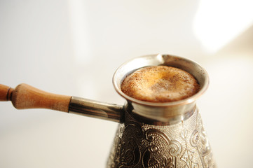 Fototapeta premium Brewing turkish coffee in cooper cezve. Rising foam close up. White background