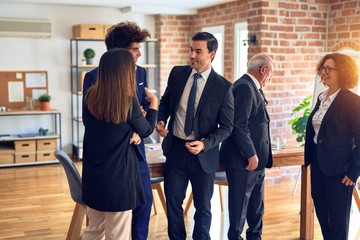 Fototapeta premium Group of business workers smiling happy and confident in a meeting. Standing with smile on face speaking relaxed at the office.