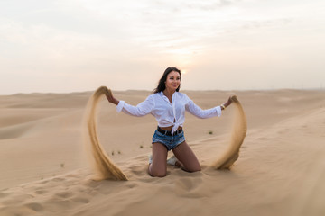Fototapeta na wymiar Young sexy woman playing with sand in the dunes desert.