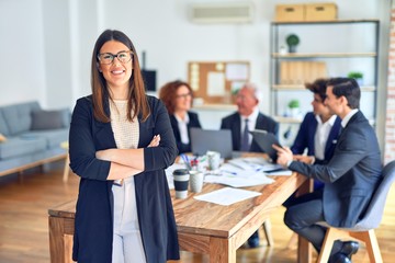 Group of business workers smiling happy and confident working together in a meeting. One of them, standing with smile on face looking at camera at the office.