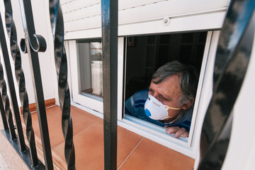 Man with mask looking out the window