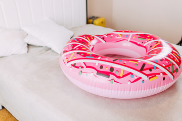 Summer vacation on quarantine, pink donut tube and pillows on the bed, home self-isolation in summer 2020