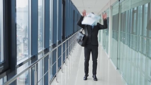 Confident young businessman leaving office tosses papers and goes forward