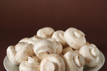 raw mushrooms on a plate on dark brown background
