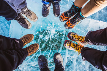 Traveller people foot standing on cracks surface of the natural ice in frozen water at Olkhon...