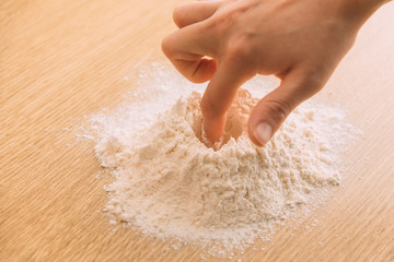 Mano haciendo un hueco en una montaña de harina