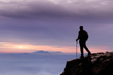 hiker on mountain peak at sunset