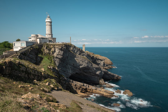 Scenic landscape of white lighthouse on cliff seashore of Costa Brava in sunny day